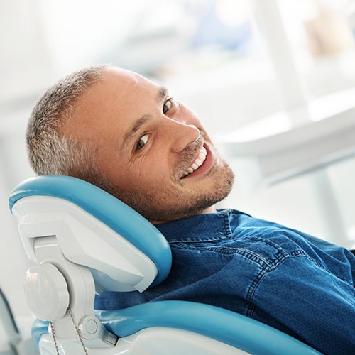 A man smiling while in a dental chair.